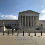 Court’s Latest Ruling Sets Up Major Showdown Supreme Court building with flag and people outside.