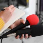 NFL Star Jumps In: Tafoya Wins Minnesota GOP Primary Journalist holding two microphones while writing in a notebook