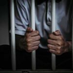 person gripping prison bars