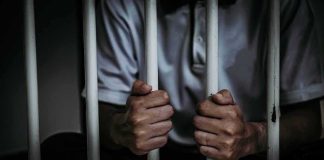Criminal Complaint Filed Against Influencer person gripping prison bars
