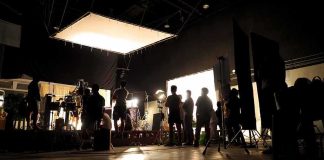 film crew silhouetted on a studio set with bright lights