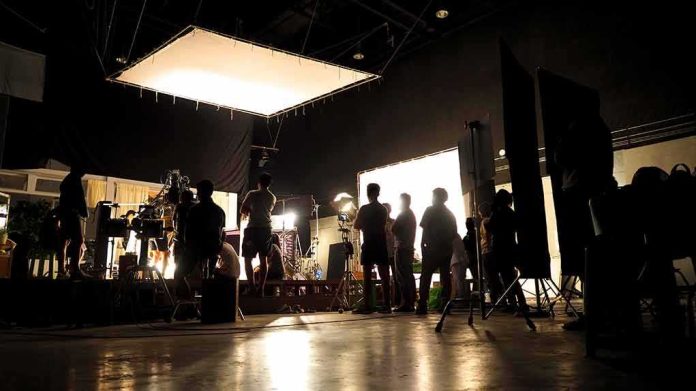film crew silhouetted on a studio set with bright lights