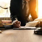Mistrial Deepens Debate Over Evidence Lawyer writing at desk with scales and gavel