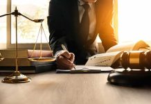 Lawyer writing at desk with scales and gavel