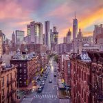 City street leading to a modern skyline at sunset