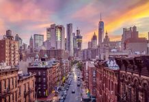 City street leading to a modern skyline at sunset