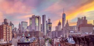 City street leading to a modern skyline at sunset