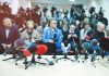 Row of microphones at a press conference with audience and cameras behind