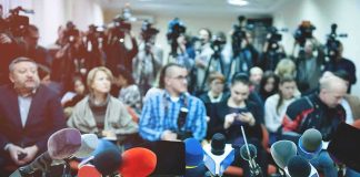 Culture War: Lakers Lineup Talk Takes a Turn Row of microphones at a press conference with audience and cameras behind