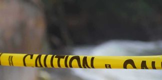 Yellow caution tape stretched across a blurred outdoor scene