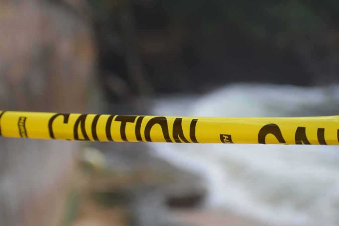 shutterstock_1251848416 Yellow caution tape stretched across a blurred outdoor scene