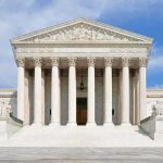 States Win as Supreme Court Upholds Transgender Athlete Laws Front view of the Supreme Court building with large columns and steps under a blue sky
