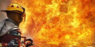 Firefighter spraying water at a large blaze