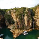 Boats anchored in a canyon lagoon with a waterfall
