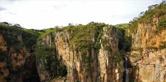Boats anchored in a canyon lagoon with a waterfall