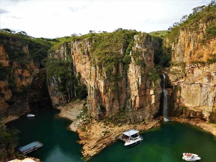 shutterstock_1443070154 Boats anchored in a canyon lagoon with a waterfall