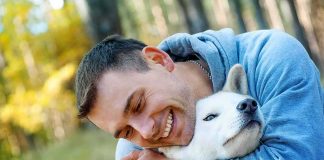 man hugging a white dog outdoors