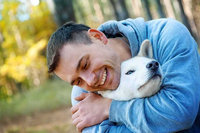 man hugging a white dog outdoors
