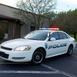 Police car with flashing lights parked outside a building
