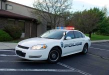 Police car with flashing lights parked outside a building