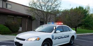 5-Year-Old Dies in Hot Car, Parents Charged Police car with flashing lights parked outside a building