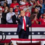 Republicans Put Trump at the Heart of the Midterms man in suit points from a stage at a political rally