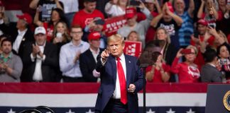 Republicans Put Trump at the Heart of the Midterms man in suit points from a stage at a political rally