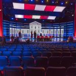 Democrats Face a Civilized Civil War Debate stage with red and blue lighting and empty audience seats
