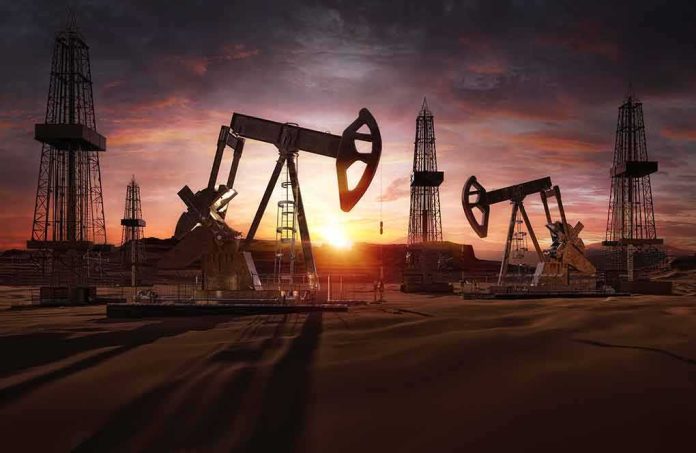 Oil pumpjacks and derricks at sunset in a desert field