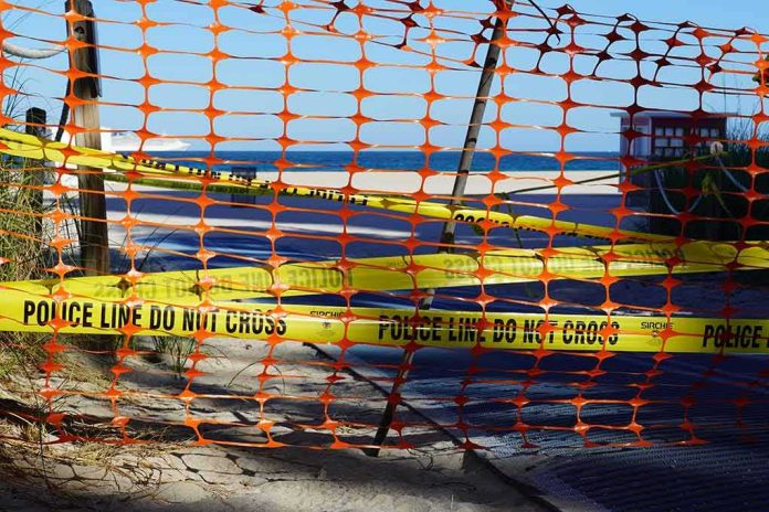shutterstock_1687026364-1 Orange safety net and yellow police tape blocking a beach access