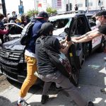 World Cup Chaos: Car Explodes Into Crowd Protesters surround and damage a police vehicle on a city street