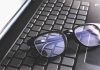 Black eyeglasses resting on a laptop keyboard