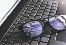 Black eyeglasses resting on a laptop keyboard