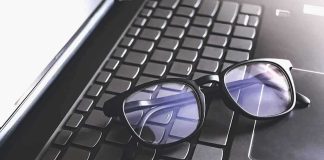 Black eyeglasses resting on a laptop keyboard