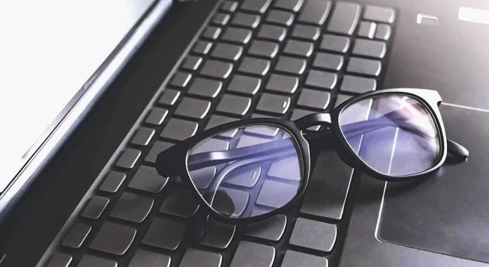shutterstock_1748103815 Black eyeglasses resting on a laptop keyboard