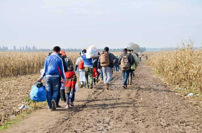 shutterstock_1752619412-2 Group of people walking along a muddy farm road with bags and backpacks