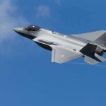 Stealth fighter jet banking in a clear blue sky