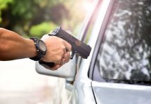 hands holding a handgun aimed near a car window
