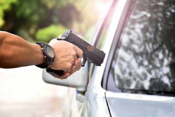 shutterstock_1820663960 hands holding a handgun aimed near a car window