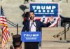 man speaking at a political rally podium