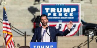 man speaking at a political rally podium
