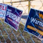 Campaign signs on a chain-link fence