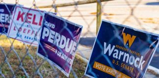 Campaign signs on a chain-link fence
