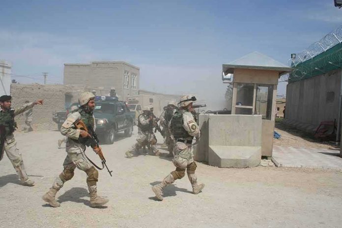 shutterstock_1931171405-2 Soldiers in desert uniforms run past a checkpoint amid dust
