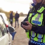 Police officer using a smartphone during a roadside stop
