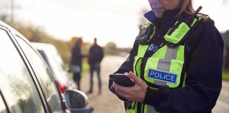 Police officer using a smartphone during a roadside stop