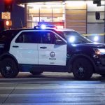 Police SUV blocks an intersection at night with lights flashing
