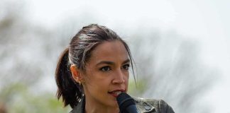 AOC speaking into a handheld microphone outdoors