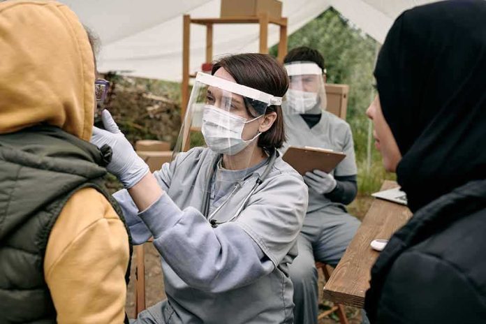 Healthcare worker in PPE examines a patient at an outdoor clinic
