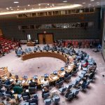 NATO Pushes Dialogue Amid Rising Tensions Delegates seated around a circular conference table in a large chamber